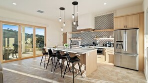 A modern kitchen with a large island, bar stools, a stainless steel refrigerator, and patterned backsplash. - Mission de los Robles by Avantstay Vineyard Views + King Suites + Patio Paso Robles Wine Country (Paso Robles)