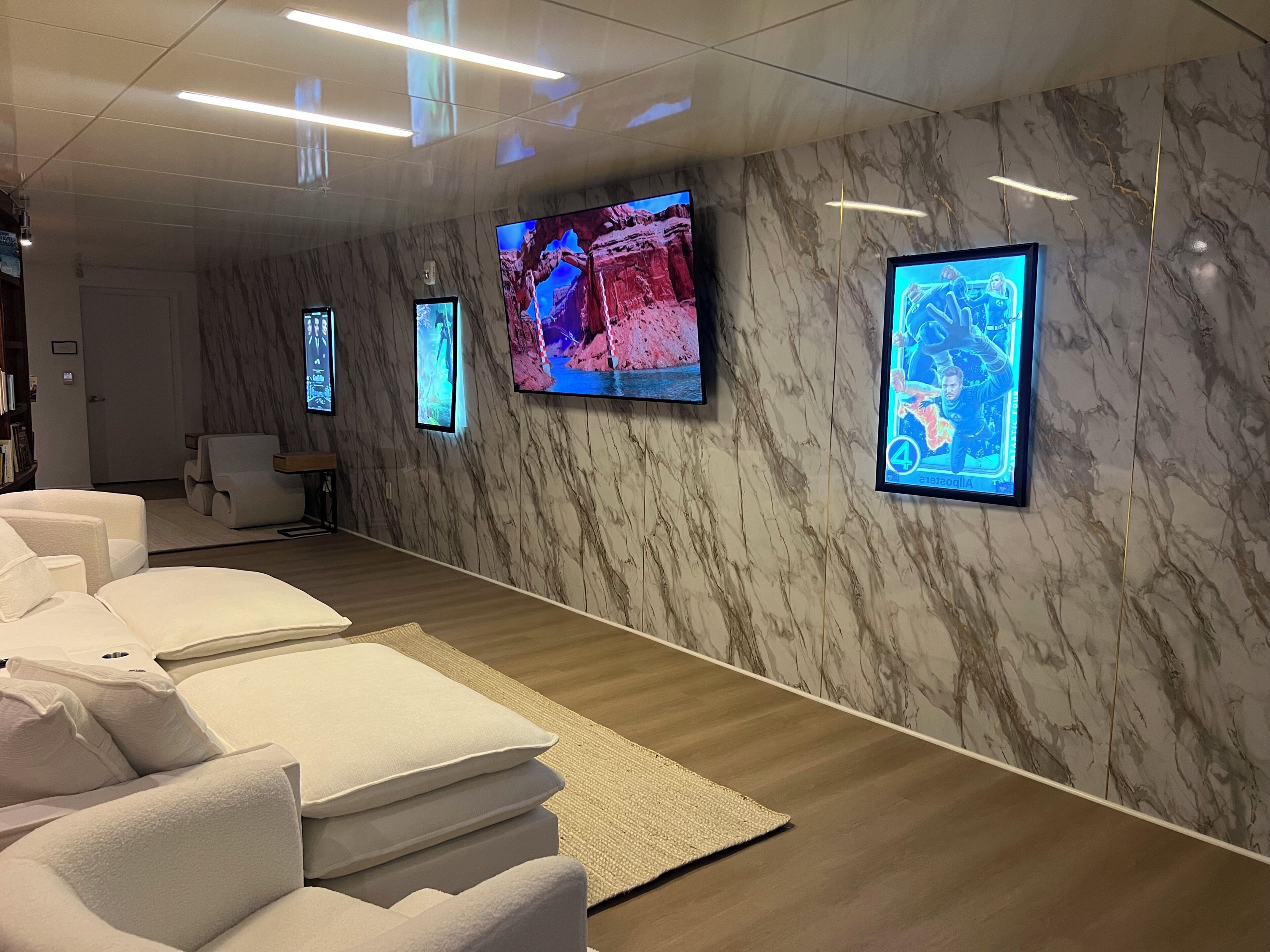 Un spa moderno con varias camillas de masaje, un televisor montado en la pared y una pared con diseño de mármol.