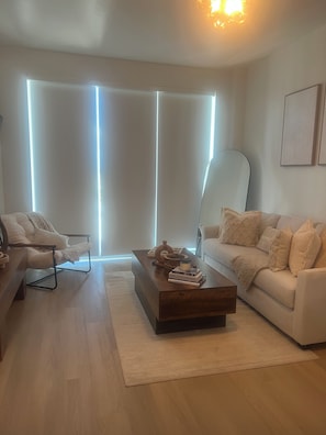 Un salon moderne comprenant un canapé, un fauteuil, une table basse et un lampadaire.