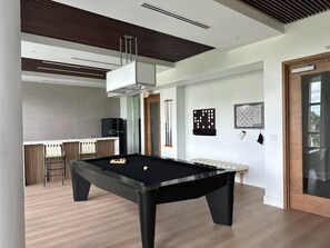 Une table de billard moderne dans une pièce bien éclairée, avec un coin cuisine en arrière-plan.