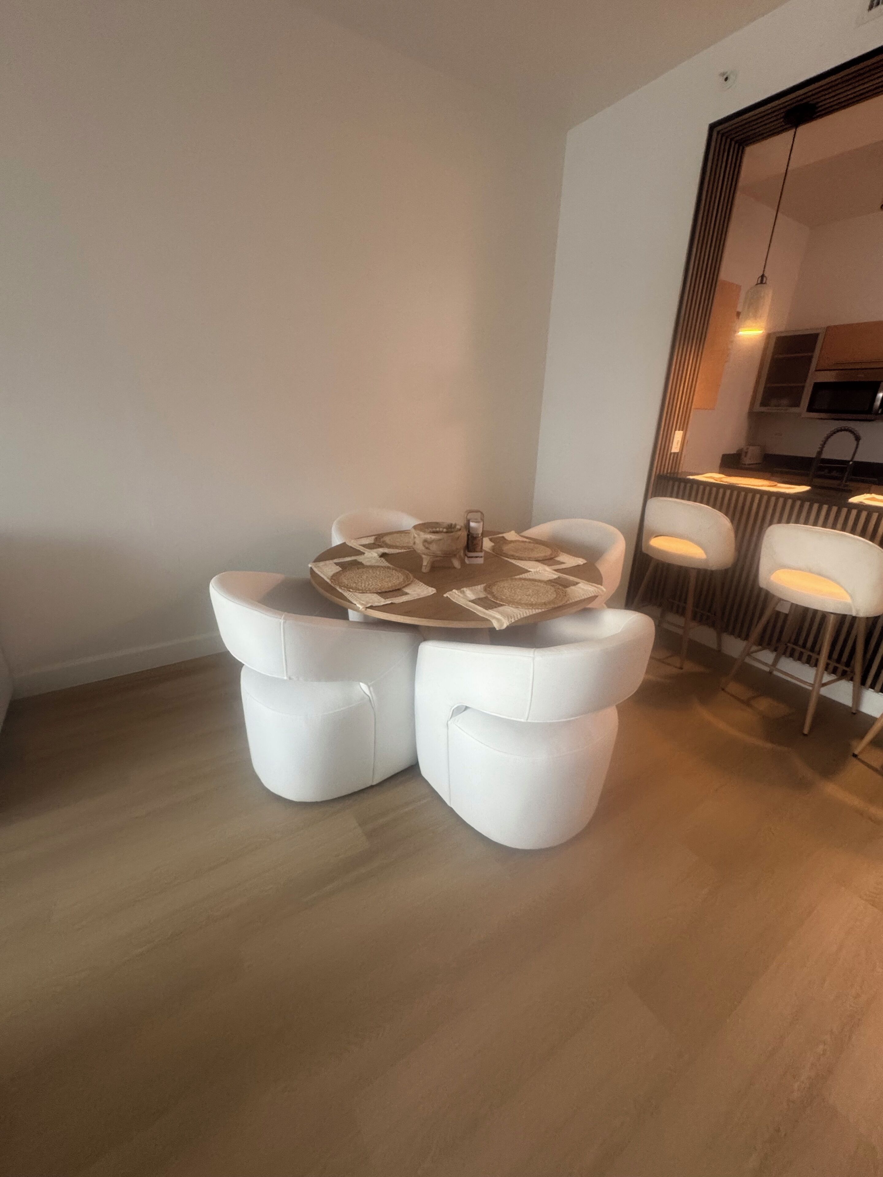 Un espace repas moderne avec une table ronde et deux chaises blanches rembourrées.