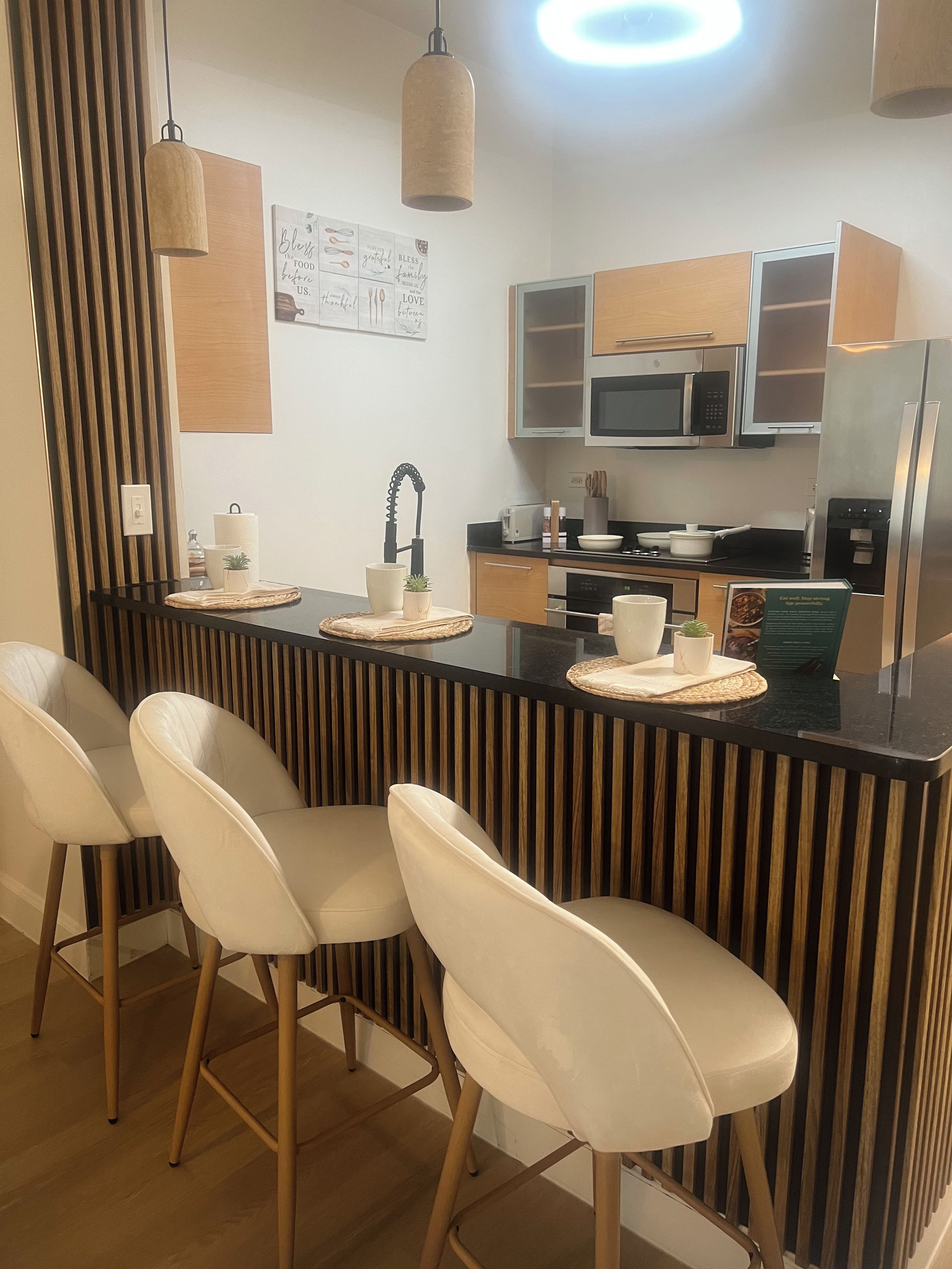 A modern kitchen with a central island, bar stools, and stainless steel appliances.