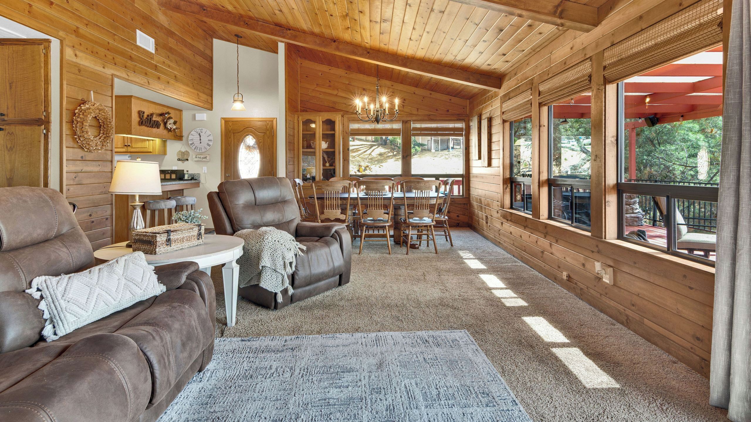 A cozy cabin interior with a living room, dining area, and large windows.