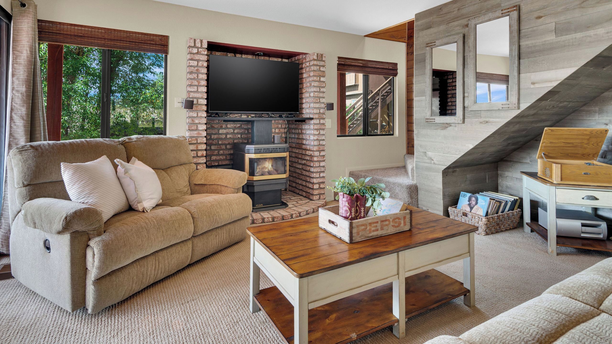 A cozy living room with a fireplace, a sofa, a coffee table, and a staircase.