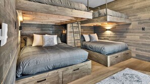A bunk bed room with wooden walls, two beds with storage drawers, a ladder, and a small table with a lamp. - Naci Lakeview Retreat by Avantstay Game Room + Bar + Lake Views Gated Marina, Ramps + Pool (Bradley)
