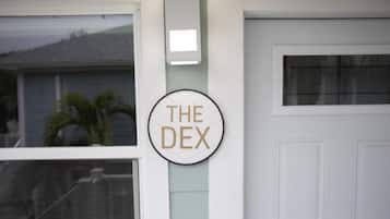 Een witte deur met een raam en een rond bord met de tekst 'THE DEX'.