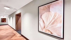 A hallway with a wooden floor, a framed artwork on the wall, and a door at the end. - Miami Central Suites (Miami)