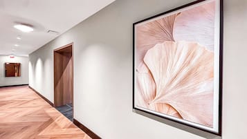 Un pasillo con piso de madera, un cuadro enmarcado en la pared y una puerta al final.
