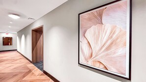 A hallway with a wooden floor, a framed artwork on the wall, and a door at the end. - Miami Central Suites (Miami)