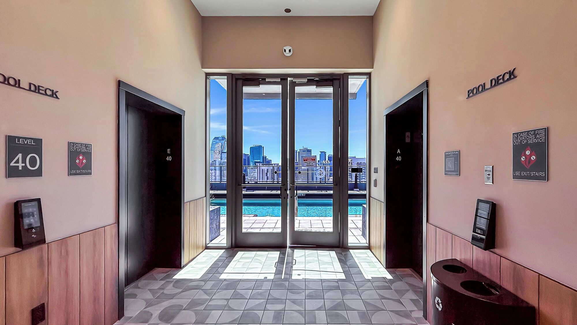 A hotel lobby with a view of a city skyline through glass doors, a level sign, and a fire safety sign.