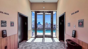 A hotel lobby with a view of a city skyline through glass doors, a level sign, and a fire safety sign. - Miami Central Suites (Miami)