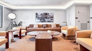 Una sala de estar moderna con un sofá, sillones, una mesa de centro y un cuadro de un paisaje urbano en la pared.