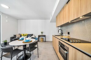 Una cocina moderna con una isla central, horno empotrado y un comedor con mesa redonda y sillas.