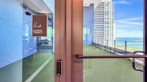 A corridor leading to a balcony with a view of a high-rise building and a body of water. - Miami Central Suites (Miami)