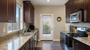 A kitchen with granite countertops, stainless steel appliances, and dark wood cabinets. - Tranquility by Avantstay Spa + Firepit + BBQ Minutes to Downtown Paso Robles (Paso Robles)