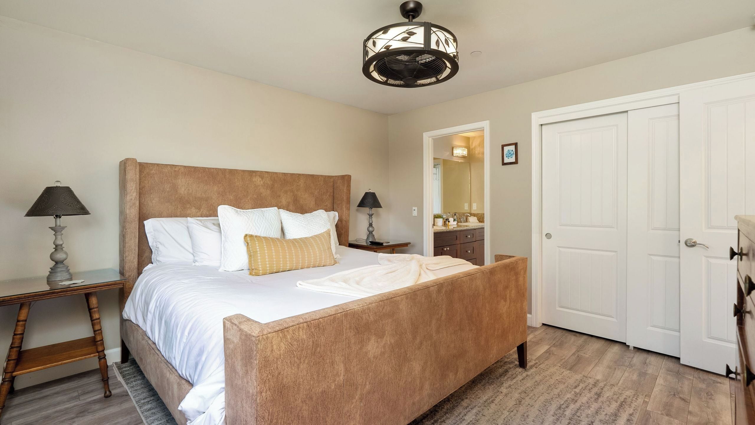 A bedroom with a wooden bed, two bedside lamps, a mirror, and a white door.