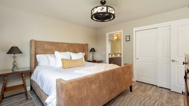 Un dormitorio con una cama de madera, dos lámparas de noche, un espejo y una puerta blanca.