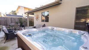 Patio con jacuzzi, mobiliario exterior y cerca de madera.