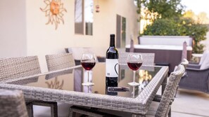 A glass table with two wine glasses and a bottle, surrounded by wicker chairs. - Tranquility by Avantstay Spa + Firepit + BBQ Minutes to Downtown Paso Robles (Paso Robles)
