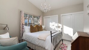 A bedroom with a bed, a chair, a desk, a chandelier, and two doors. - Tranquility by Avantstay Spa + Firepit + BBQ Minutes to Downtown Paso Robles (Paso Robles)