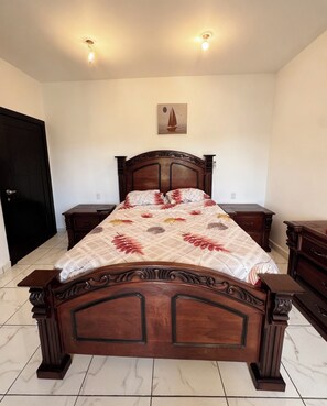 A bedroom with a wooden bed, two bedside tables, a black door, and a wall-mounted light fixture. - Apartment in the best location in Las Terrenas, Near Beaches and Supermarkets (Las Terrenas)