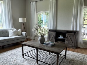 A living room with a sofa, a coffee table, a vase with flowers, a lamp, and a fireplace.