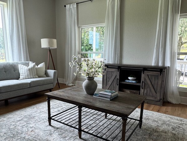 A living room with a sofa, a coffee table, a vase with flowers, a lamp, and a fireplace.