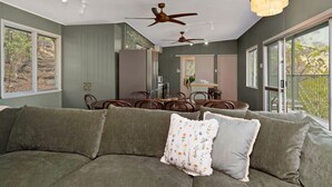 A modern living room with a sectional sofa, dining table, ceiling fans, and large windows. - AMAROO ARCADIA – GABUL WAY (Arcadia)