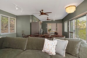 A modern living room with a sectional sofa, dining table, ceiling fans, and large windows. - AMAROO ARCADIA – GABUL WAY (Arcadia)