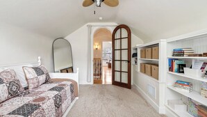 A bedroom with a bed, a bookshelf, a mirror, and a door leading to another room. - Backyard Vines on Olive by Avantstay Spa + BBQ + Big Backyard Walk to Downtown Paso (Paso Robles)