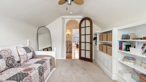 A bedroom with a bed, a bookshelf, a mirror, and a door leading to another room. - Backyard Vines on Olive by Avantstay Spa + BBQ + Big Backyard Walk to Downtown Paso (Paso Robles)