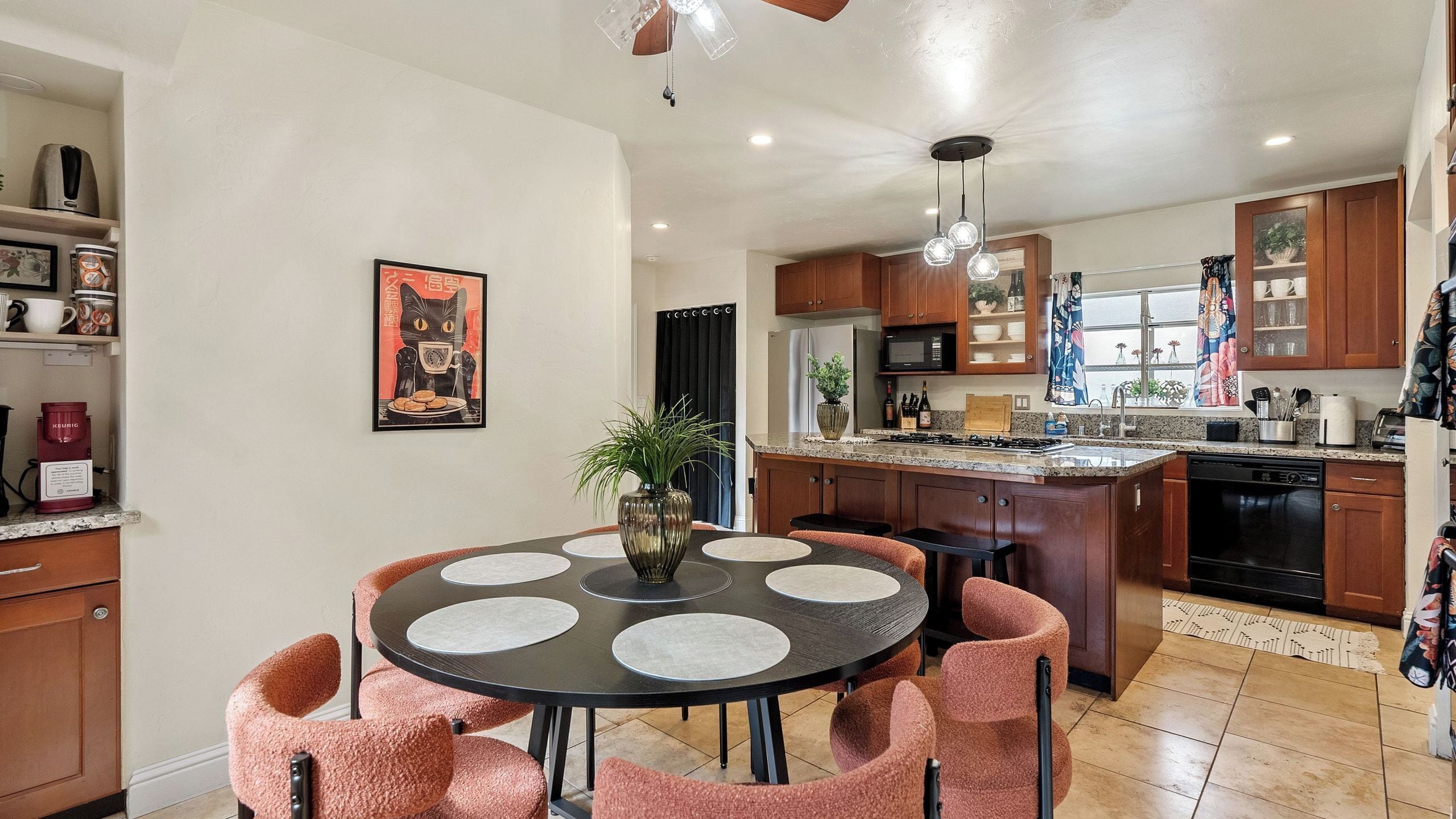 A modern kitchen with a central island, dining table with chairs, and a coffee machine.