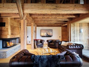 A spacious living room with a fireplace, leather sofas, and a large window.