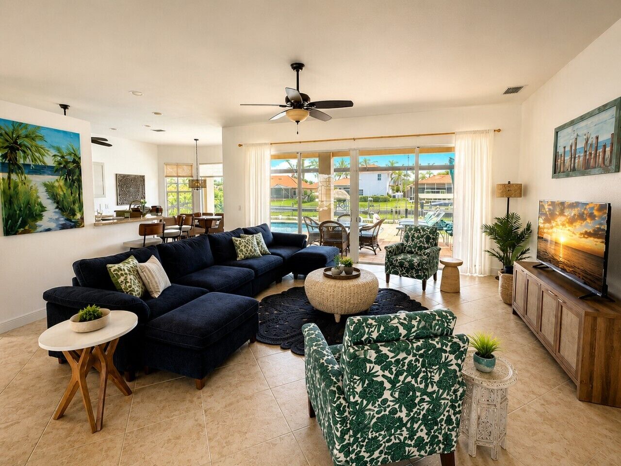 A spacious living room with a dark blue sectional sofa, a round coffee table, and a television on a wooden cabinet.