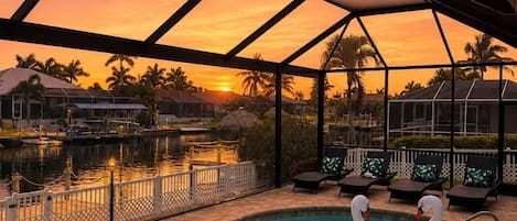 Una piscina con dos flotadores con forma de cisne, rodeada por una zona techada con vistas a palmeras y casas.