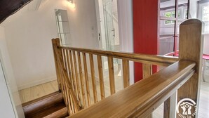 A wooden staircase with a handrail leading to a room with a glass shower and a red accent wall. - La Petite Quinoise - PLOUER SUR RANCE (PLOUER SUR RANCE)