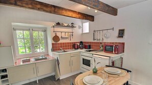A compact kitchen with a window, a microwave, and a dining table set for two. - La Petite Quinoise - PLOUER SUR RANCE (PLOUER SUR RANCE)