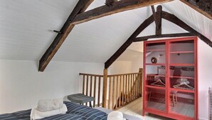 A bedroom with a sloped ceiling, a bed with striped bedding, a red wardrobe, and a small table. - La Petite Quinoise - PLOUER SUR RANCE (PLOUER SUR RANCE)