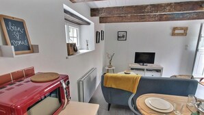 A cozy living room with a red vintage stove, a television, and a blue sofa. - La Petite Quinoise - PLOUER SUR RANCE (PLOUER SUR RANCE)