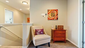 A hallway with a chair, a small wooden dresser, and a painting on the wall. - Sunset Summit by Avantstay Modern Kitchen + BBQ Patio Downtown Paso Robles (Paso Robles)