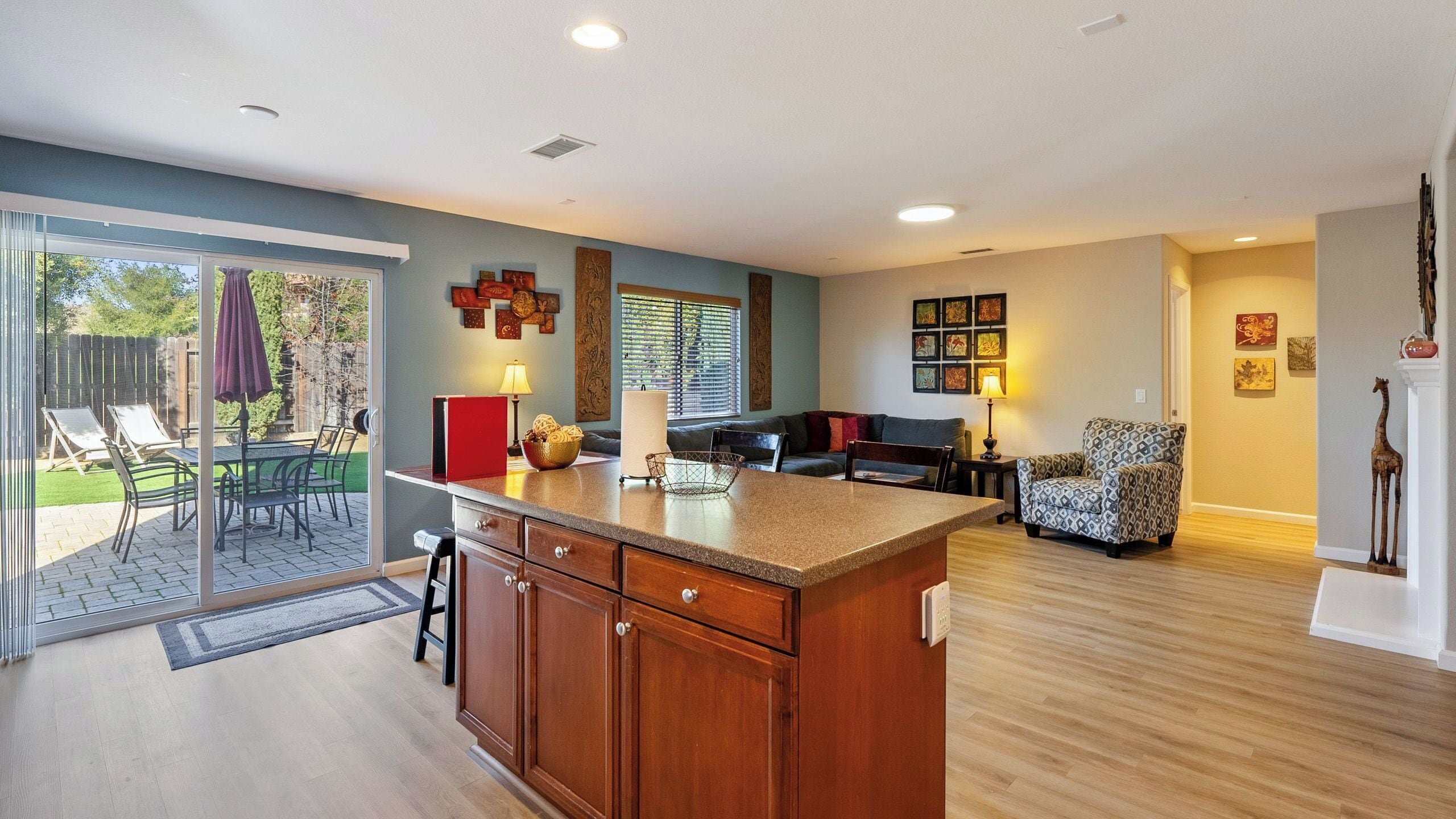 A modern kitchen with a large island, a dining area with a sofa, and a patio with outdoor furniture.