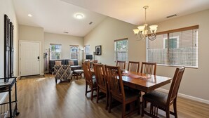 A dining area with a wooden table and chairs, a chandelier, and a television on a stand. - Sunset Summit by Avantstay Modern Kitchen + BBQ Patio Downtown Paso Robles (Paso Robles)