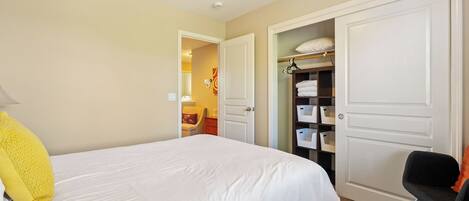 A hotel room with a bed, a chair, a wardrobe, and a closet with shelves.