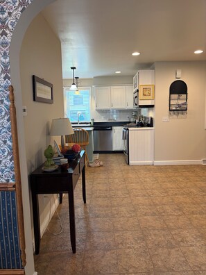 A kitchen with white cabinets, a dining area with a table and chairs, and a tiled floor. - Gorgeous 4-bedroom house in charming Dodgeville. (Dodgeville)