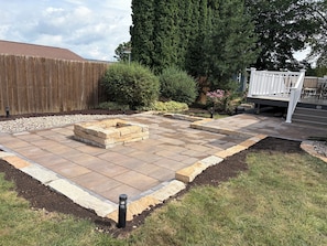 A backyard with a fire pit, a wooden fence, and a white deck. - Gorgeous 4-bedroom house in charming Dodgeville. (Dodgeville)