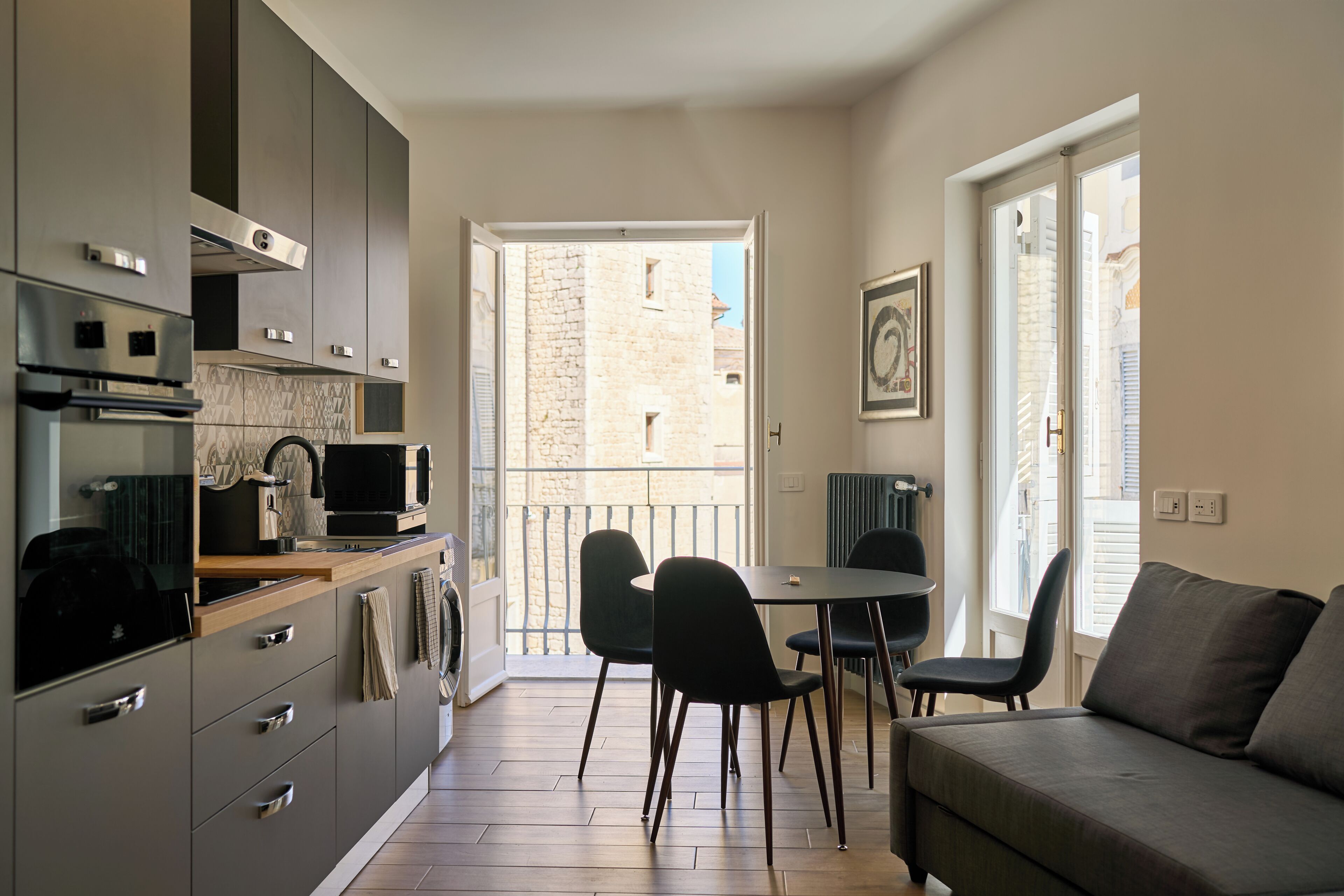 A compact kitchen with modern appliances, a dining area with a table and chairs, and a sofa.