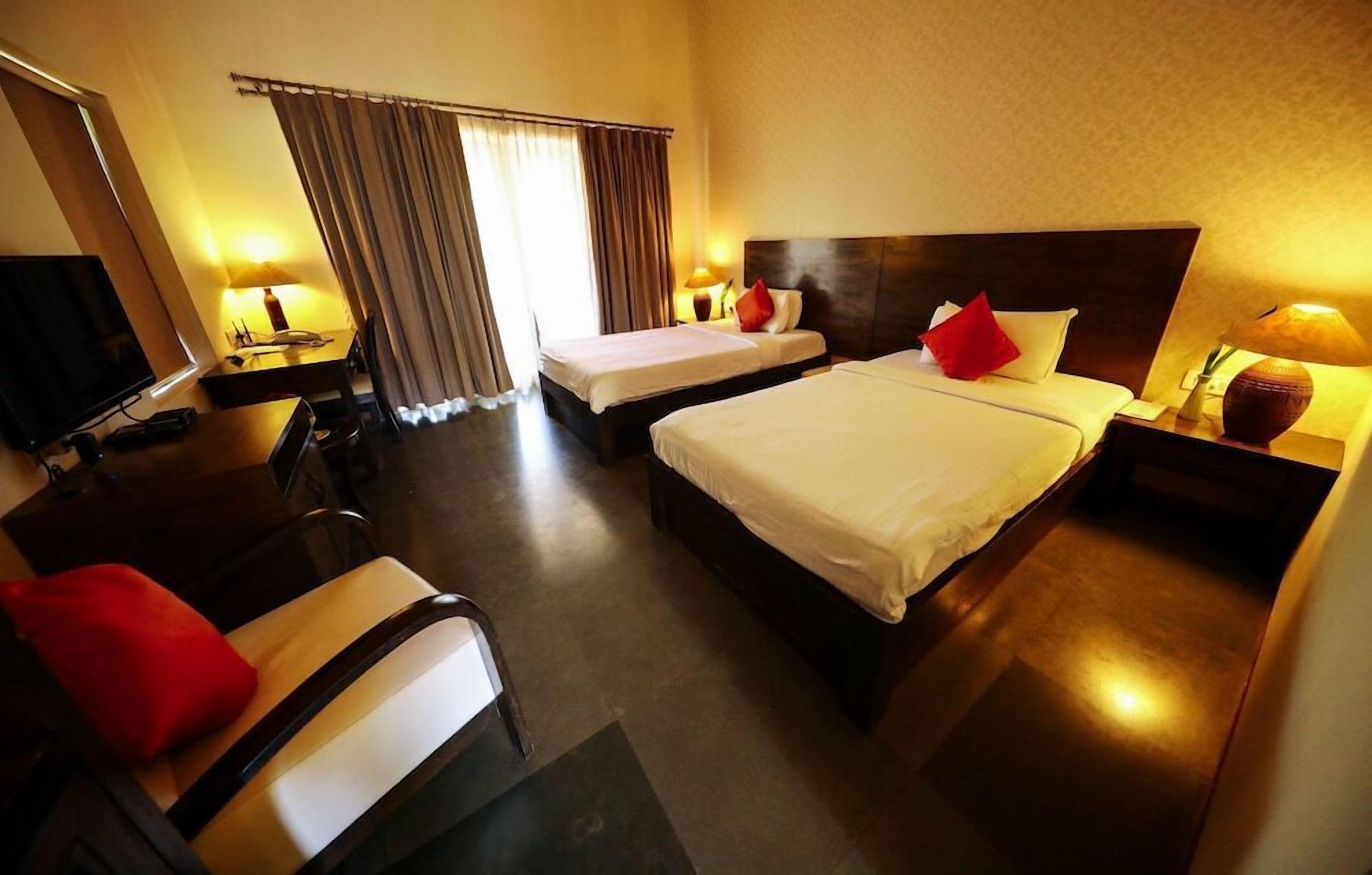 A hotel room with two beds, a desk, a chair, a TV, and a window with curtains.