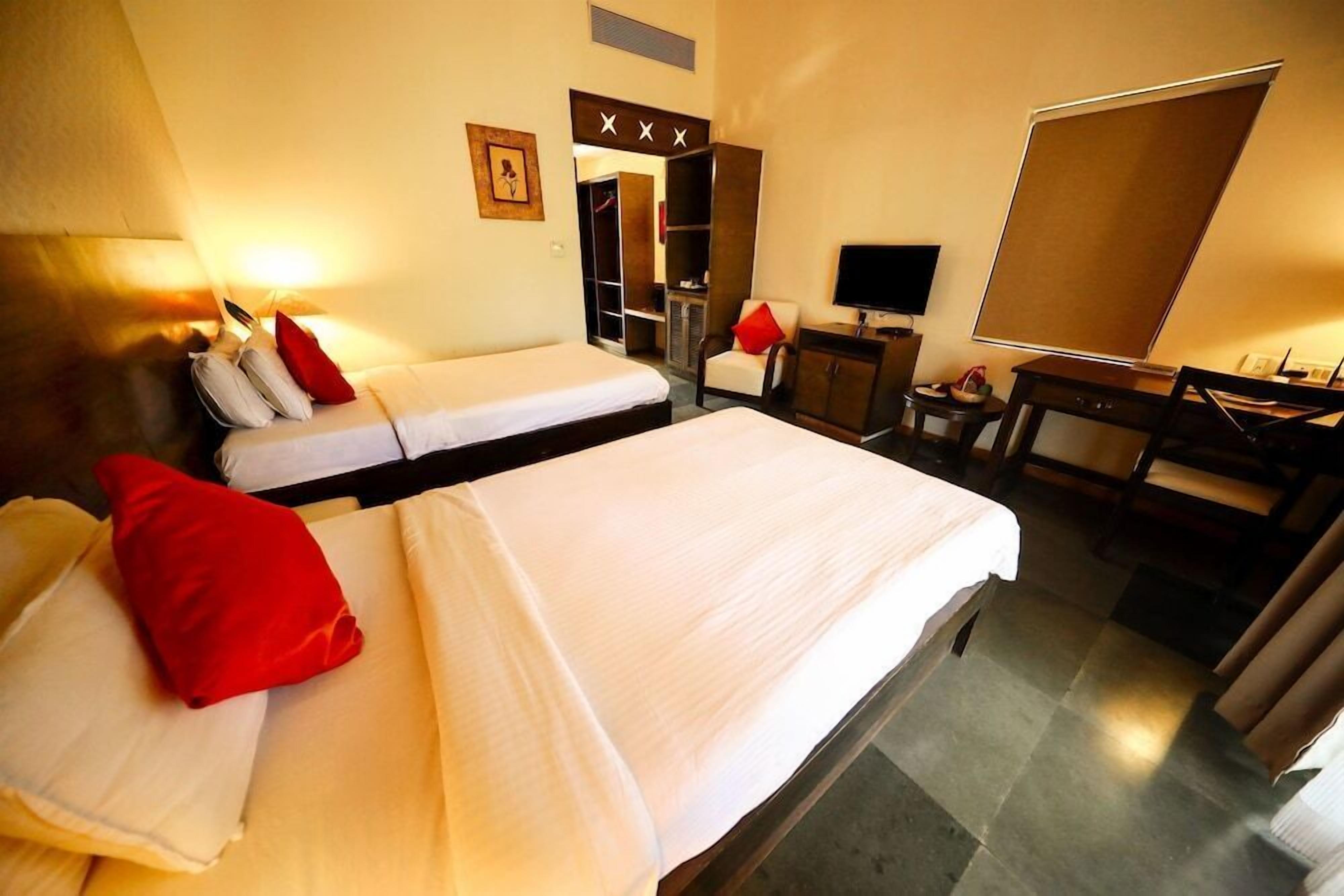 A hotel room with two beds, a desk, a chair, a television, and a wardrobe.