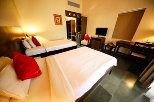 Habitación de hotel con dos camas, un escritorio, una silla, un televisor y un armario.