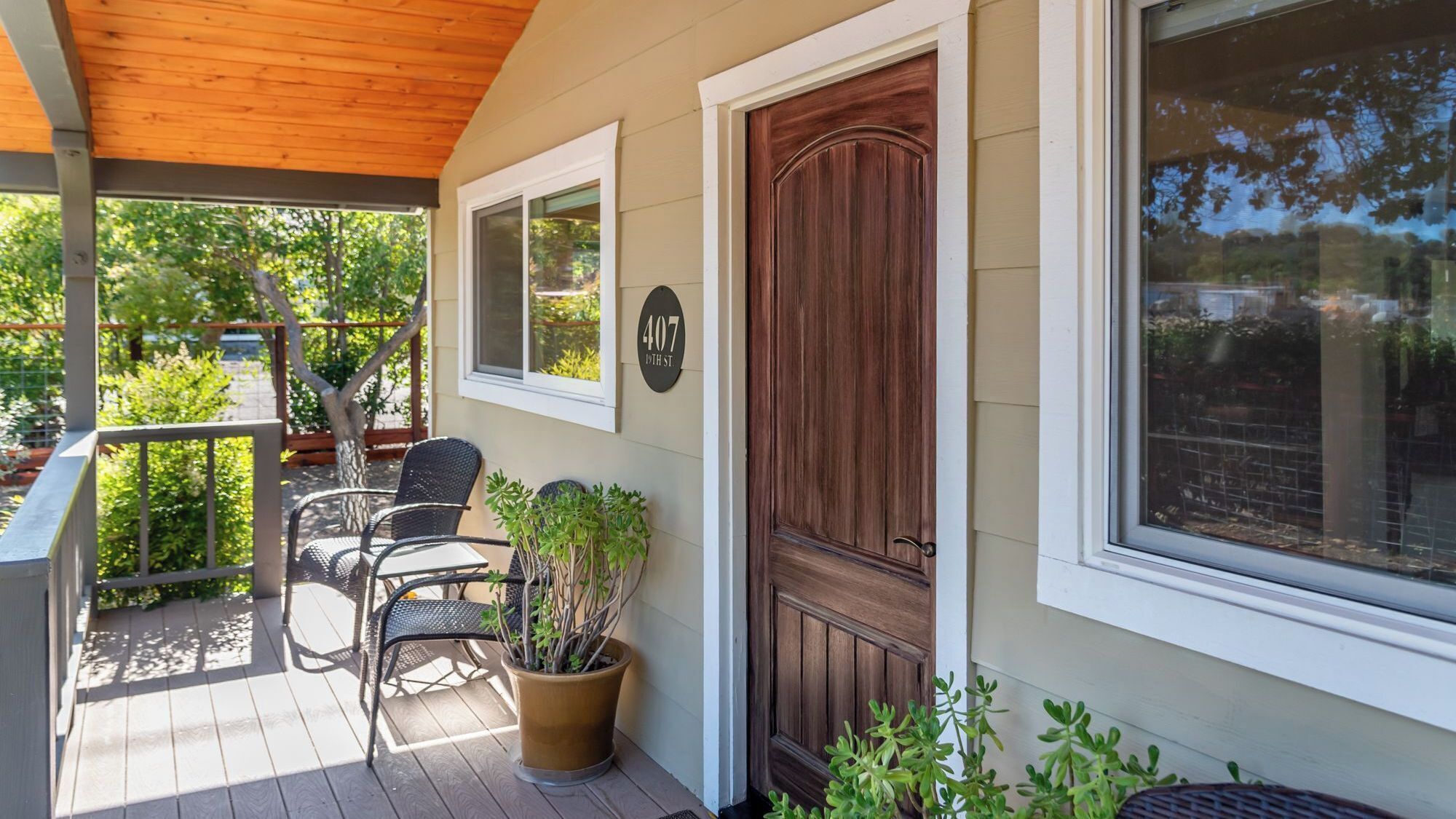 A covered porch with outdoor furniture and potted plants.